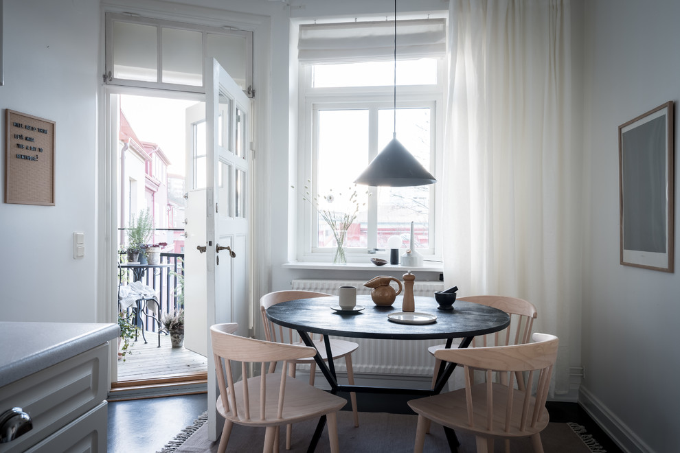This is an example of a scandinavian kitchen/dining room in Gothenburg with white walls, dark hardwood flooring and black floors.