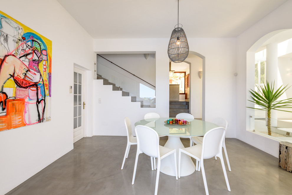 Diseño de comedor mediterráneo de tamaño medio abierto con paredes blancas, suelo de cemento y suelo gris