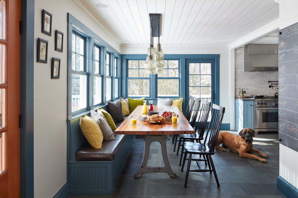 Cette photo montre une salle à manger ouverte sur la cuisine nature avec un mur blanc et un sol gris.