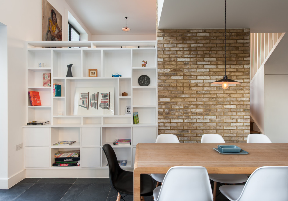 Cette image montre une salle à manger design avec un mur blanc et un sol en ardoise.