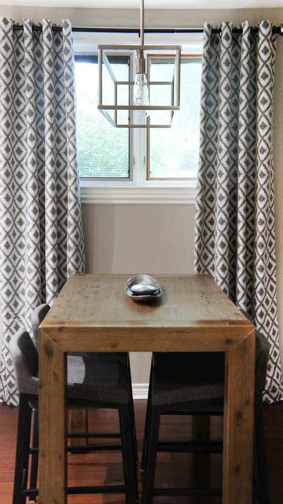 Cette image montre une salle à manger ouverte sur le salon traditionnelle de taille moyenne avec un mur gris, un sol en bois brun, une cheminée standard et un manteau de cheminée en béton.