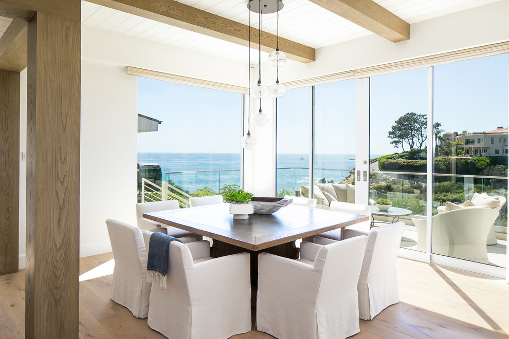 Example of a beach style light wood floor and beige floor dining room design in Los Angeles with white walls
