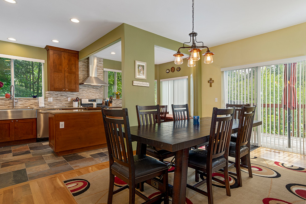 Cette photo montre une grande salle à manger ouverte sur la cuisine craftsman avec un mur multicolore, un sol en bois brun, aucune cheminée et un sol marron.