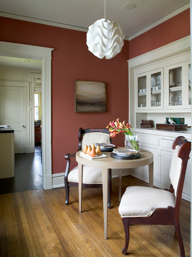 Aménagement d'une petite salle à manger classique fermée avec un mur rouge, un sol en bois brun et un sol marron.