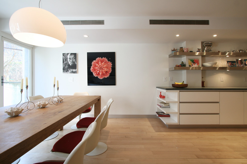 Idées déco pour une salle à manger ouverte sur la cuisine contemporaine avec un mur blanc et un sol en bois brun.