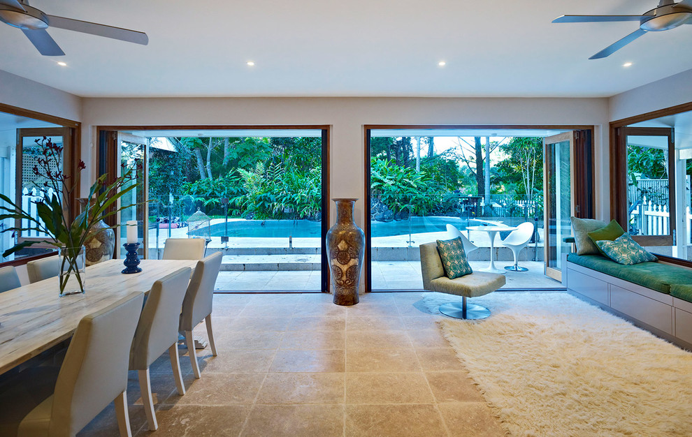 Esempio di una grande sala da pranzo aperta verso il soggiorno tropicale con pareti bianche e pavimento in pietra calcarea