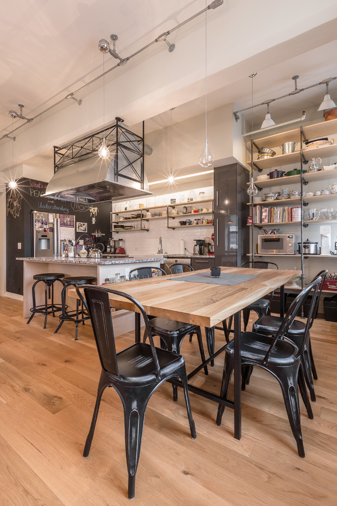 Esempio di una sala da pranzo aperta verso il soggiorno industriale con pareti beige e parquet chiaro