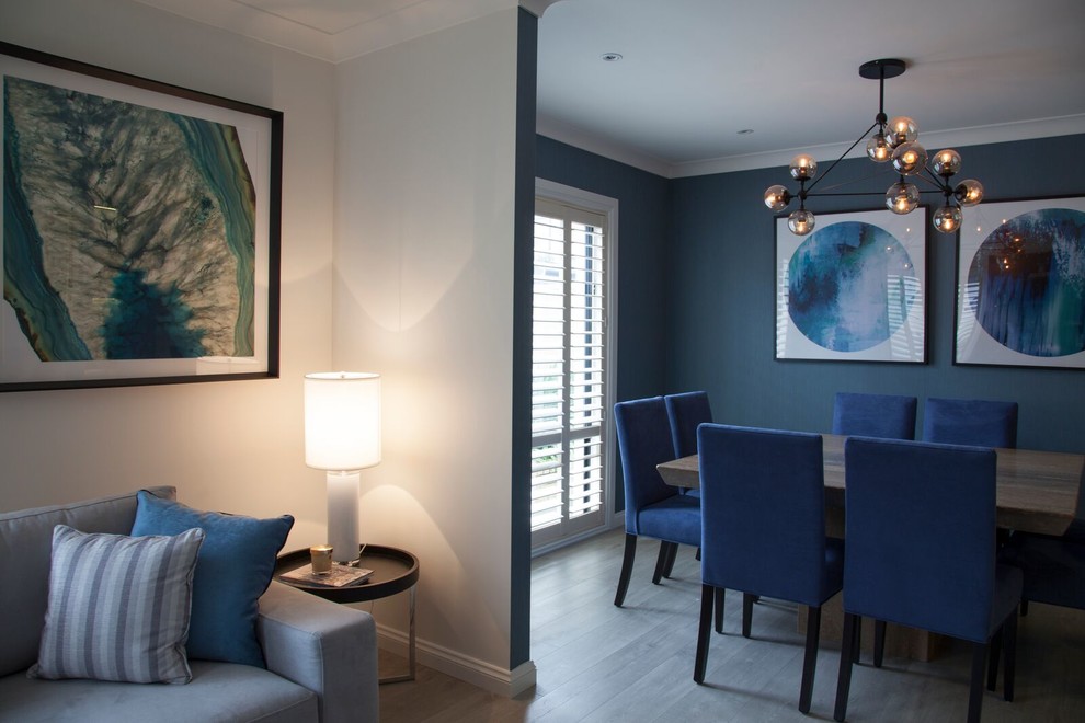 Immagine di una grande sala da pranzo aperta verso il soggiorno minimal con pareti blu e parquet chiaro