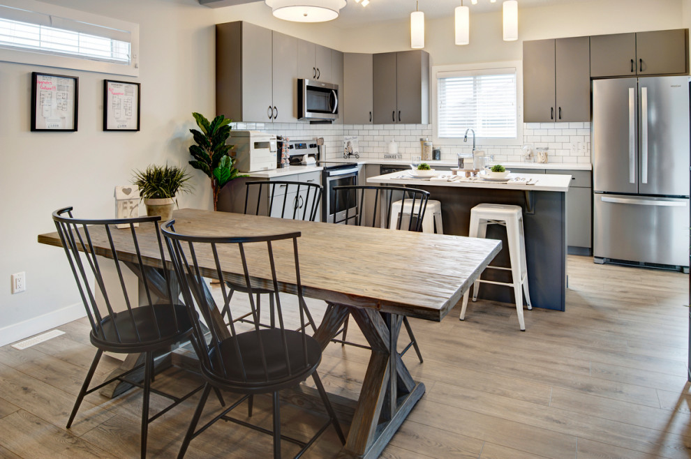 Cette image montre une petite salle à manger ouverte sur la cuisine traditionnelle avec un mur blanc, sol en stratifié et un sol gris.