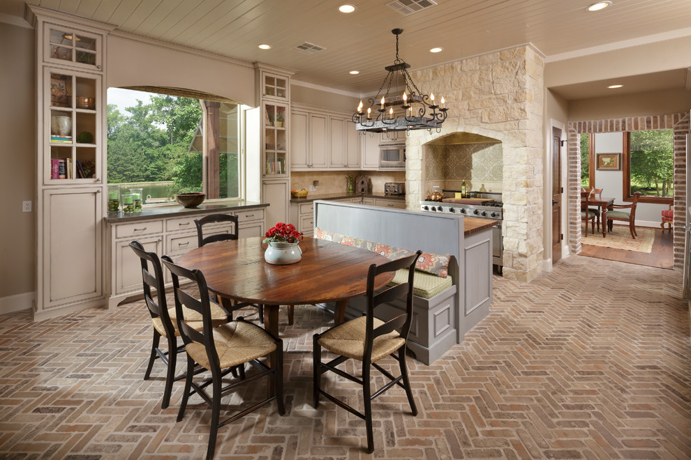 Example of a large tuscan brick floor and brown floor kitchen/dining room combo design in Houston with beige walls