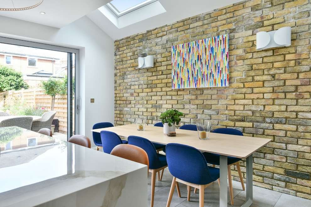 Immagine di una sala da pranzo aperta verso la cucina contemporanea con pareti bianche e pavimento grigio
