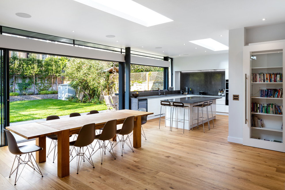 Aménagement d'une grande salle à manger ouverte sur la cuisine contemporaine avec un sol en bois brun.