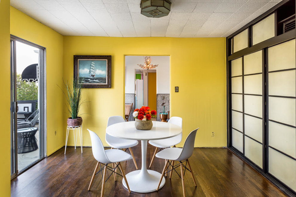 Esempio di una sala da pranzo minimalista chiusa e di medie dimensioni con pareti gialle, parquet scuro, nessun camino e pavimento marrone