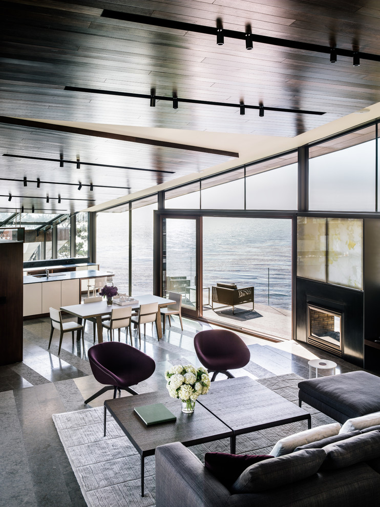 Inspiration pour une grande salle à manger ouverte sur le salon design avec une cheminée double-face, sol en béton ciré, un manteau de cheminée en métal et un sol gris.