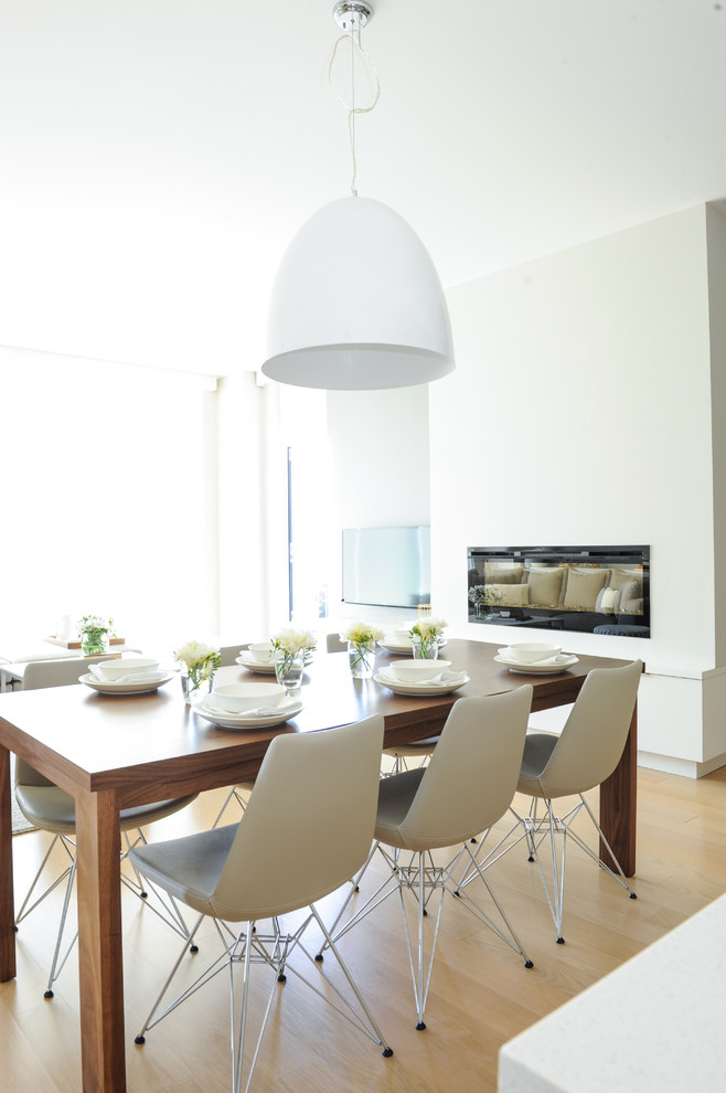 Immagine di una sala da pranzo aperta verso il soggiorno scandinava con pareti bianche e pavimento in legno massello medio