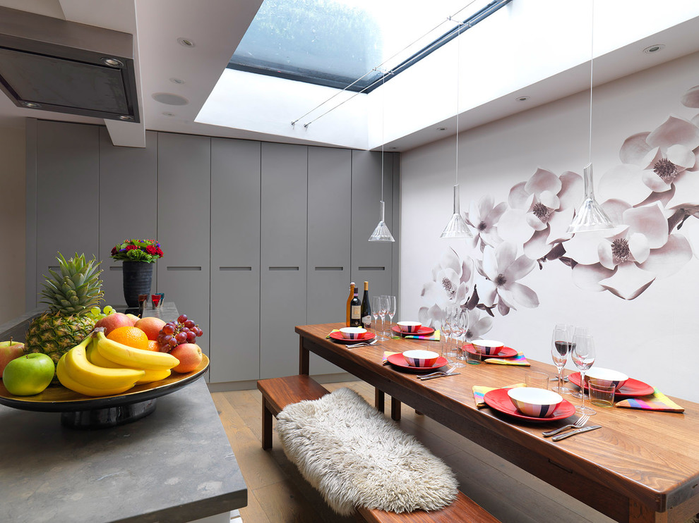 This is an example of a small contemporary kitchen/dining room in London with medium hardwood flooring, a standard fireplace and multi-coloured walls.