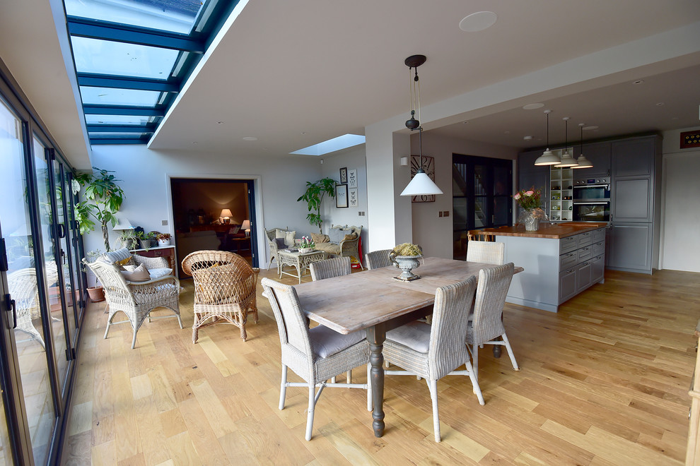 This is an example of a large contemporary kitchen/dining room in Hertfordshire with grey walls, medium hardwood flooring and beige floors.