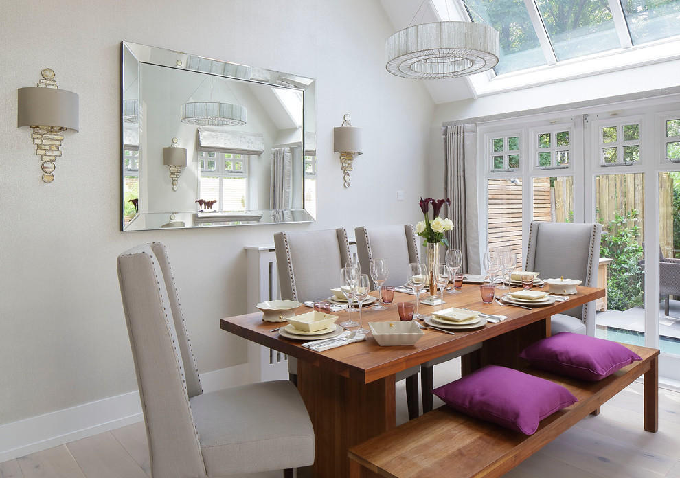 This is an example of a traditional dining room in London with white walls, light hardwood flooring and beige floors.
