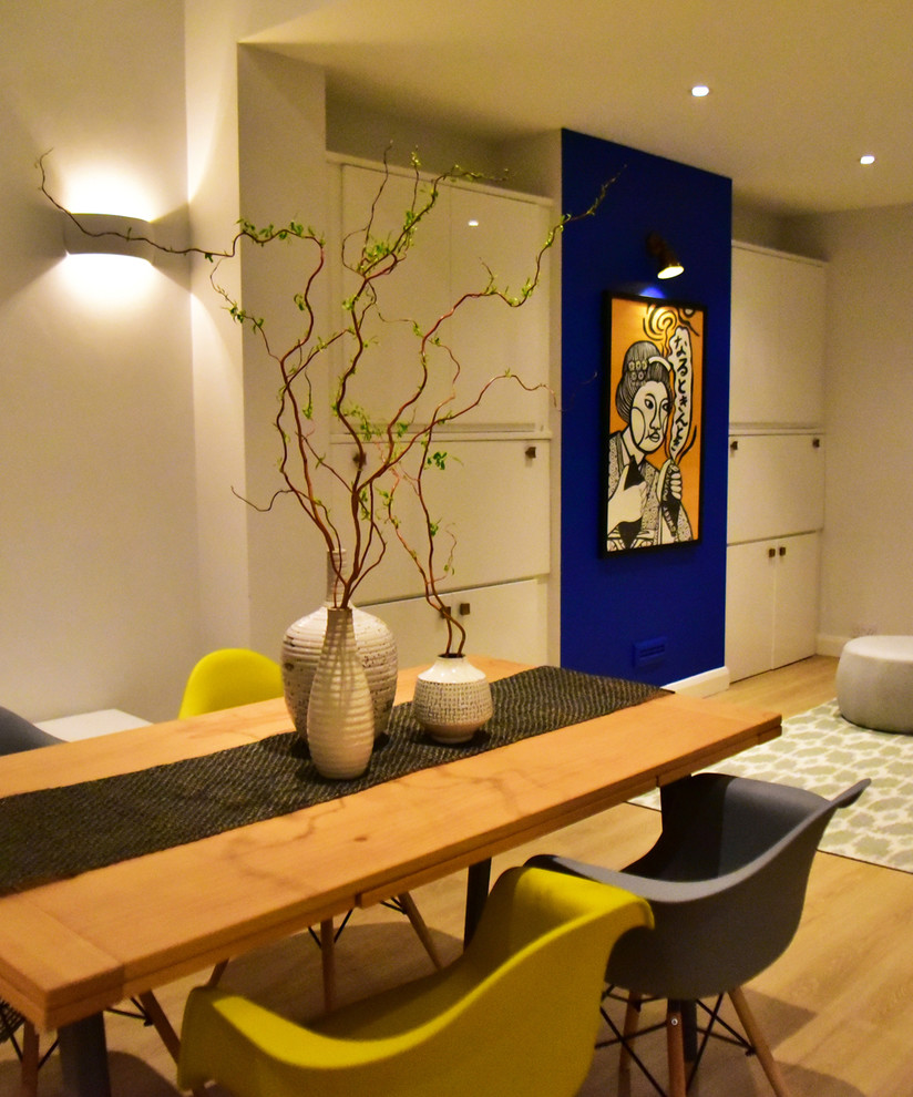 Cette image montre une salle à manger ouverte sur le salon design de taille moyenne avec un mur blanc, sol en stratifié et aucune cheminée.