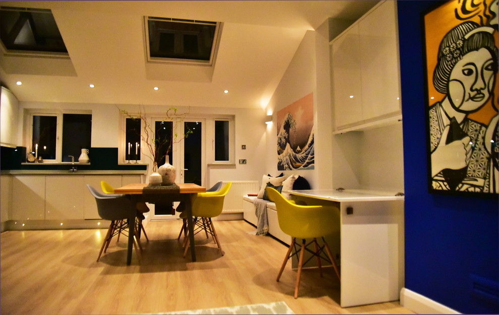 Medium sized contemporary open plan dining room in London with white walls, laminate floors and no fireplace.