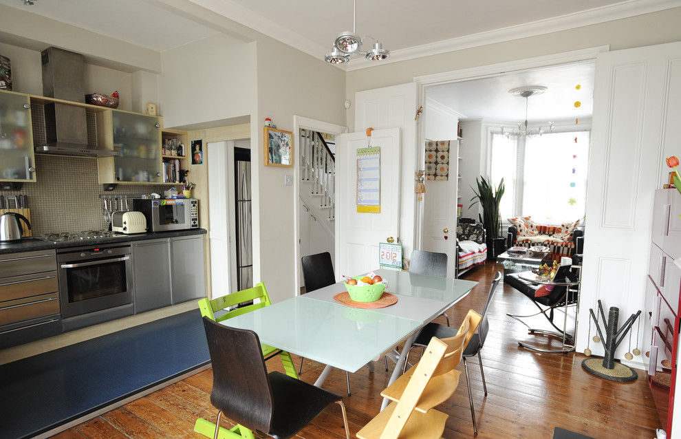Cette image montre une salle à manger ouverte sur la cuisine bohème avec un mur beige et un sol en bois brun.