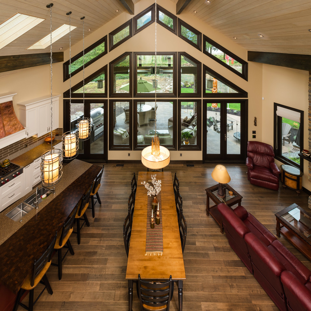 Aménagement d'une grande salle à manger ouverte sur le salon montagne avec un mur beige, un sol en bois brun et éclairage.