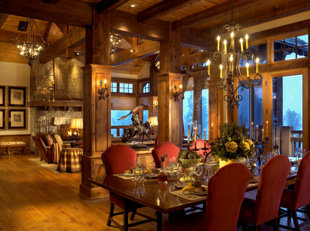 Esempio di una sala da pranzo aperta verso il soggiorno rustica con pavimento in legno massello medio e cornice del camino in pietra