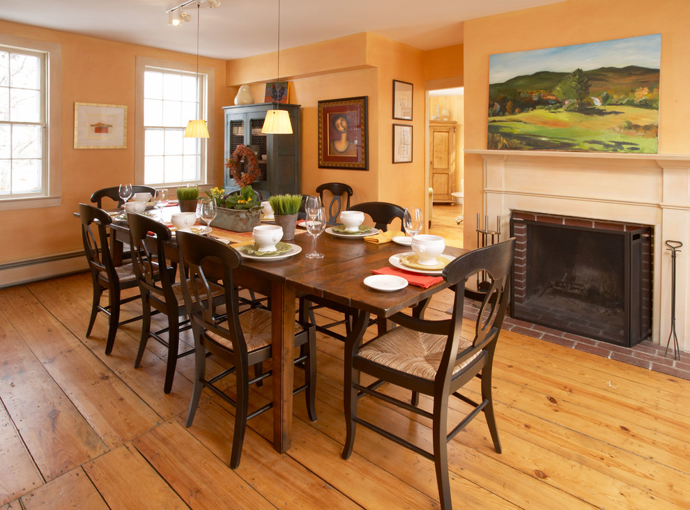 Farmhouse dining room photo in Boston with a brick fireplace and orange walls