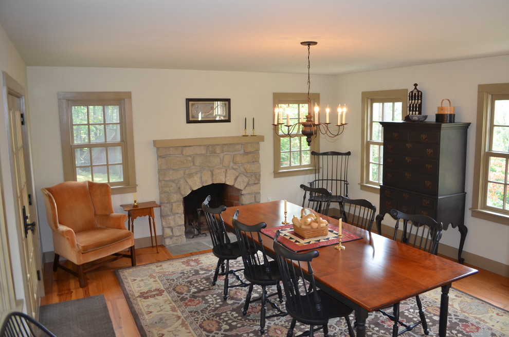 Exemple d'une salle à manger nature avec un mur beige, un sol en bois brun et un manteau de cheminée en pierre.