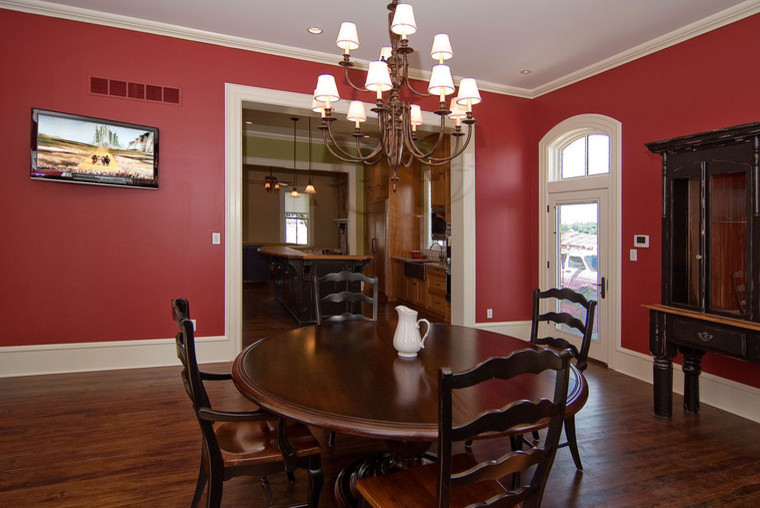 Cette photo montre une salle à manger nature fermée et de taille moyenne avec un mur rouge, parquet foncé et un sol marron.