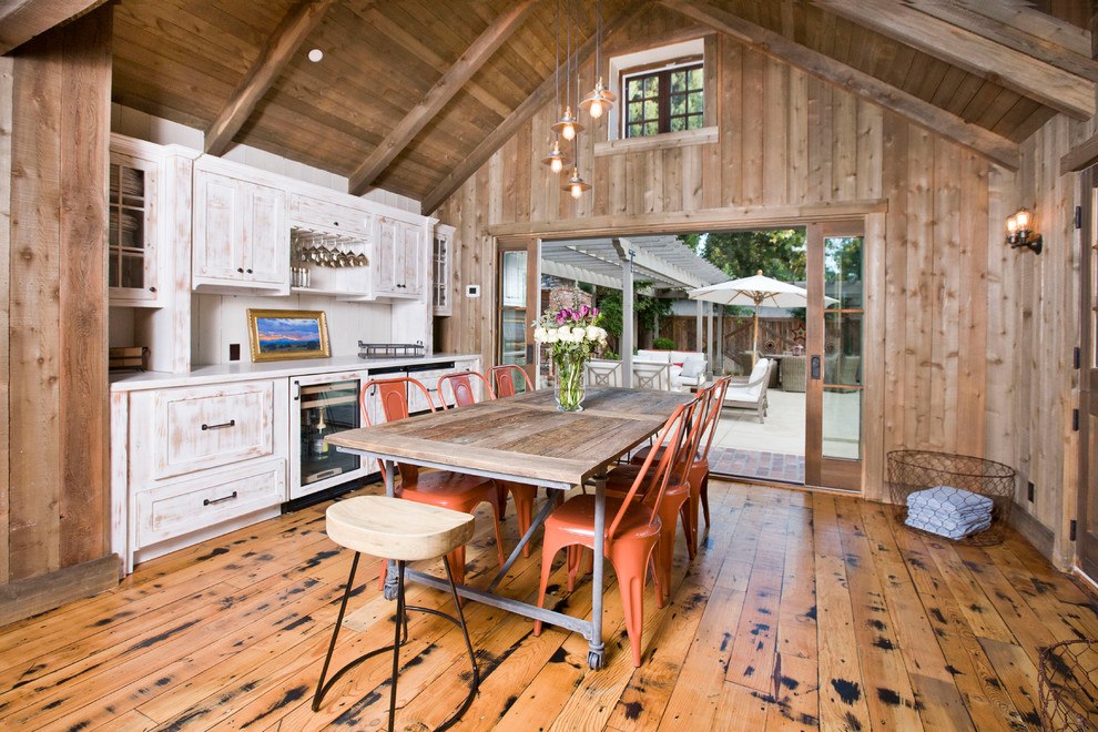 Foto di una sala da pranzo aperta verso la cucina country con pavimento in legno massello medio