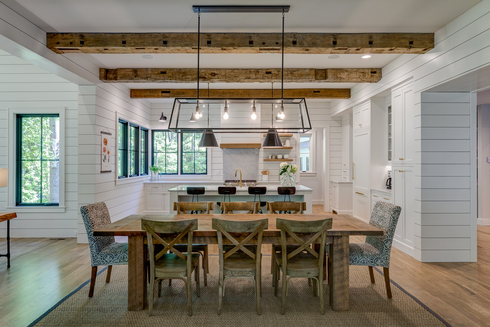 Aménagement d'une salle à manger ouverte sur le salon campagne avec un mur blanc, un sol en bois brun et un sol marron.