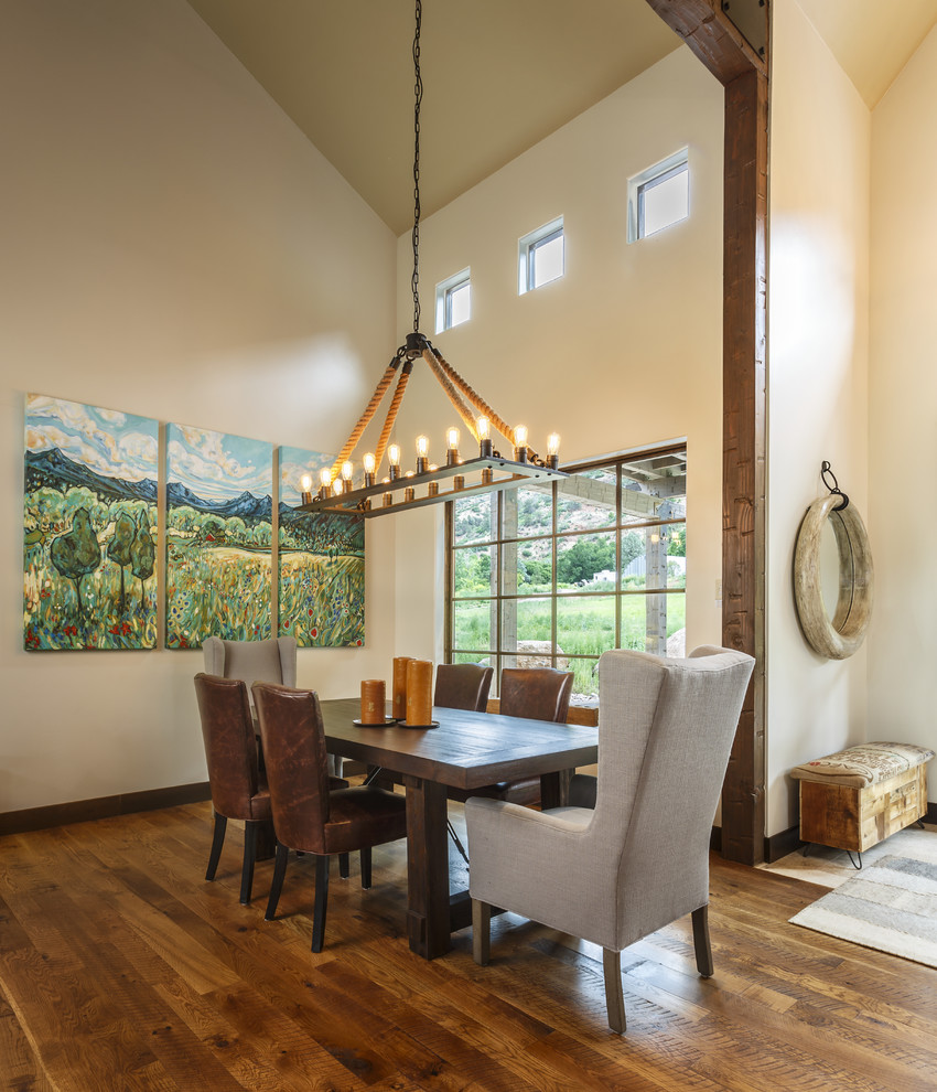 Aménagement d'une salle à manger ouverte sur le salon campagne avec un mur beige, parquet foncé et un sol marron.