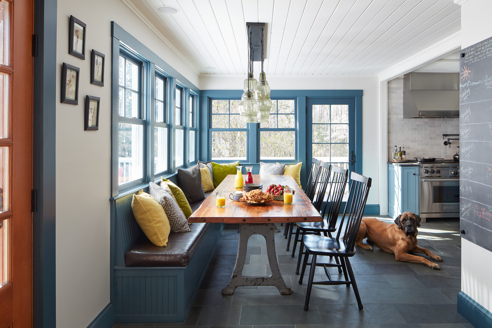 Foto di una sala da pranzo aperta verso la cucina tradizionale di medie dimensioni con pareti bianche, pavimento in ardesia e pavimento grigio