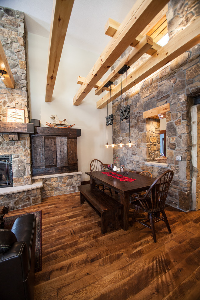 Example of a farmhouse dark wood floor dining room design in Minneapolis with white walls and a stone fireplace