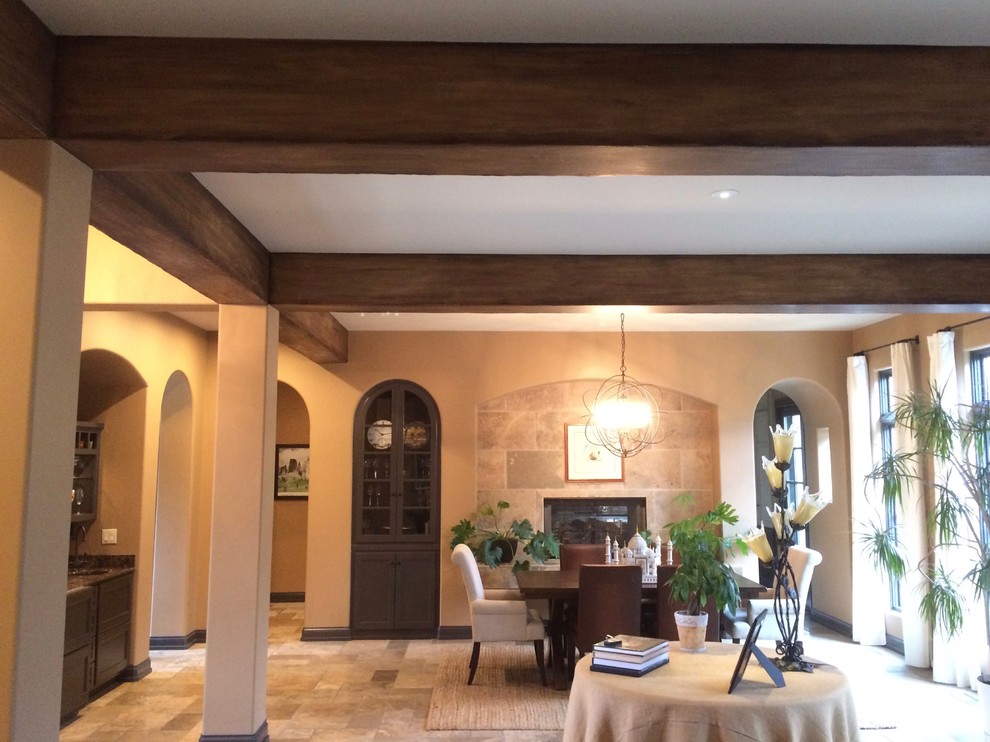 Immagine di una grande sala da pranzo aperta verso il soggiorno rustica con pareti beige, pavimento in ardesia, camino classico e cornice del camino piastrellata