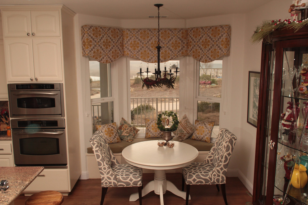 Cette photo montre une salle à manger ouverte sur la cuisine chic de taille moyenne avec un mur beige, sol en stratifié et un sol marron.