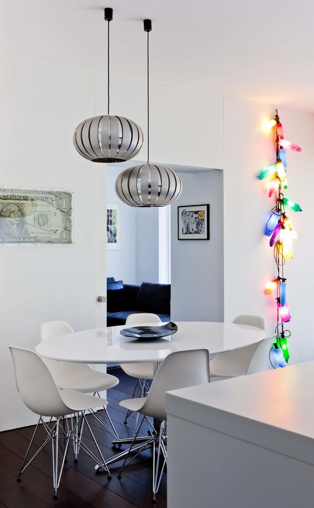Immagine di una piccola sala da pranzo aperta verso la cucina moderna con pareti bianche, parquet scuro e pavimento marrone