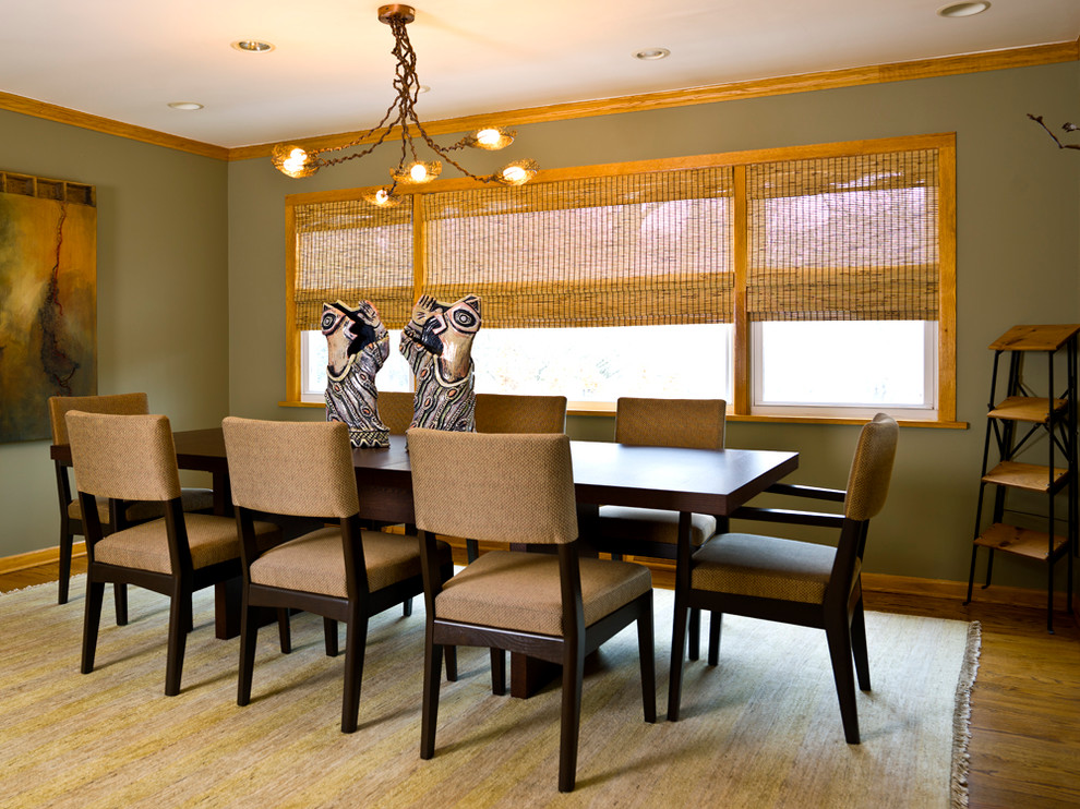 Cette image montre une salle à manger design avec un mur vert et un sol en bois brun.