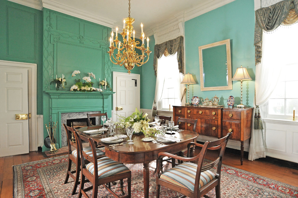 Inspiration pour une salle à manger traditionnelle avec un mur vert, un sol en bois brun et une cheminée standard.