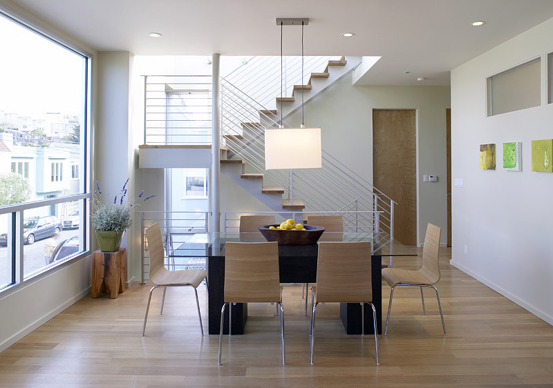 Modern dining room in San Francisco with beige floors and feature lighting.