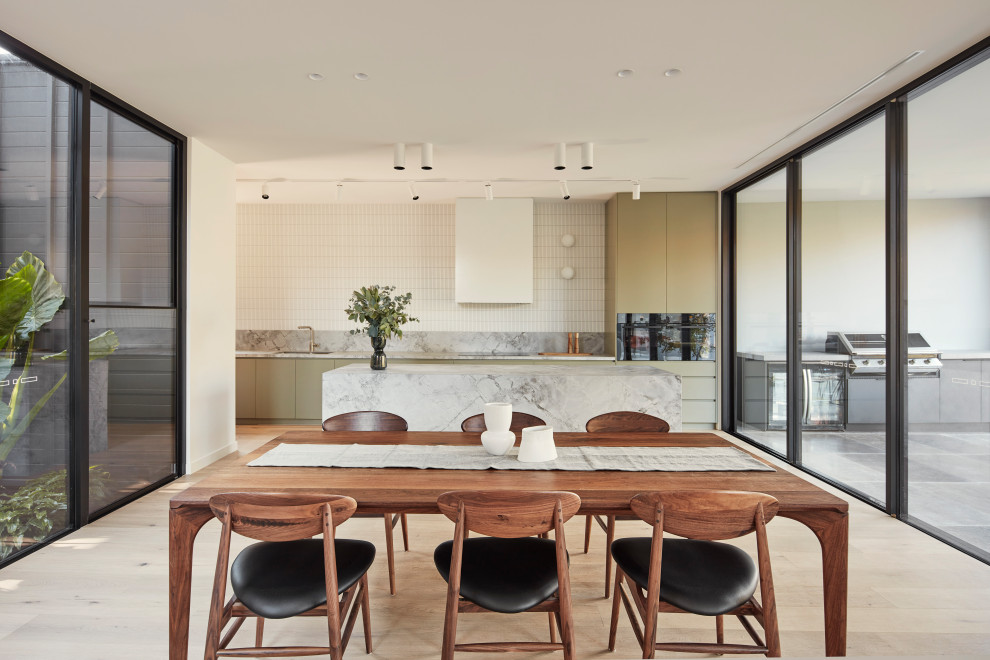 Esempio di una grande sala da pranzo aperta verso la cucina minimalista con parquet chiaro, pavimento beige e pareti bianche