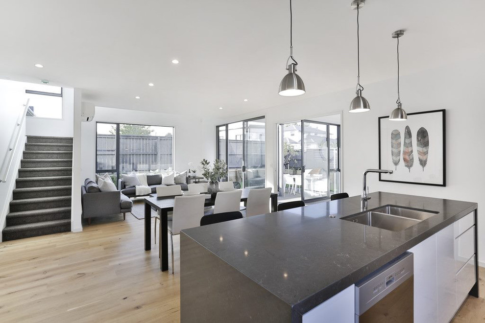 Esempio di una sala da pranzo aperta verso il soggiorno minimalista di medie dimensioni con pareti bianche, parquet chiaro e pavimento beige