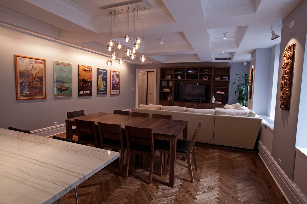 Cette photo montre une salle à manger ouverte sur le salon tendance de taille moyenne avec un mur gris et un sol en bois brun.
