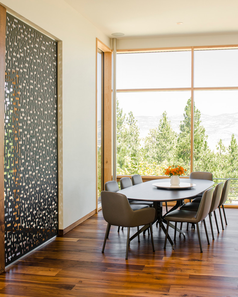 Inspiration pour une salle à manger ouverte sur le salon design avec un mur blanc et un sol en bois brun.