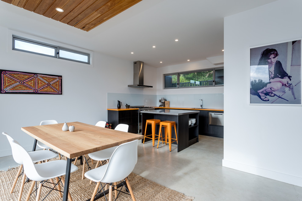 Idee per una sala da pranzo aperta verso la cucina design con pareti bianche, pavimento in cemento e pavimento grigio