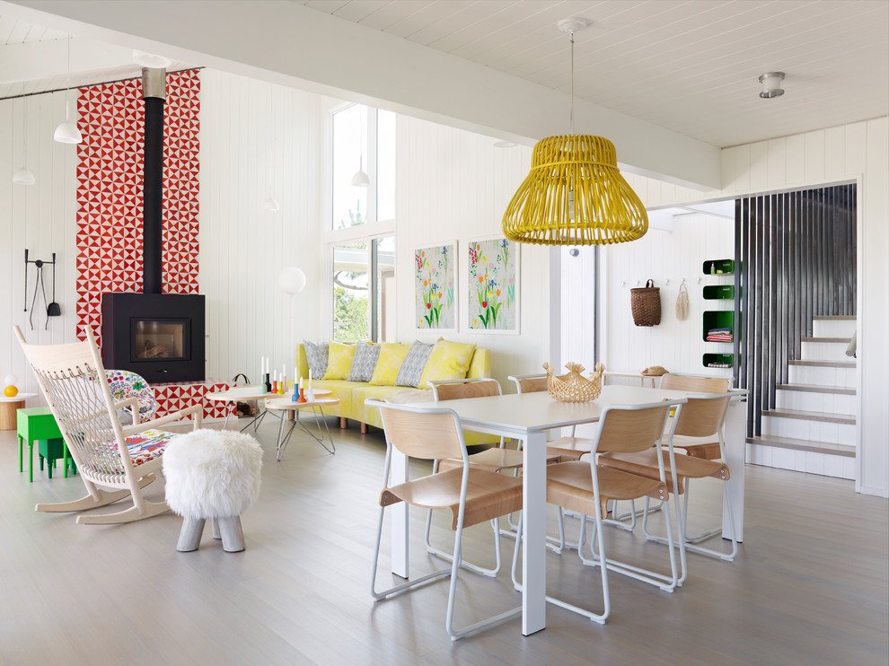 Exemple d'une salle à manger ouverte sur le salon tendance avec un mur blanc, un sol en bois brun, un poêle à bois et un sol marron.