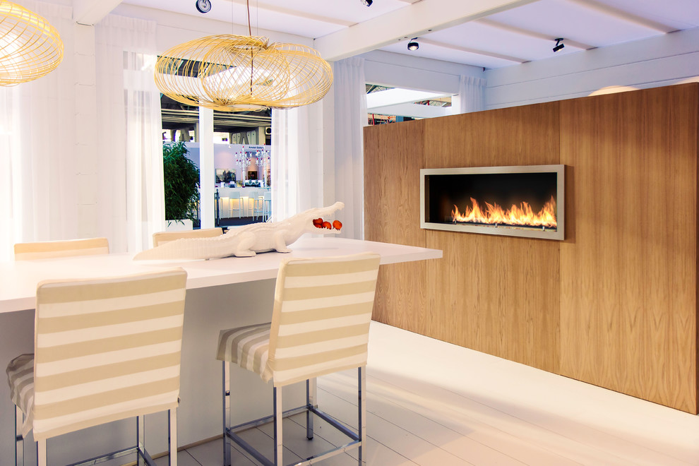На фото: кухня-столовая в стиле фьюжн с белыми стенами, деревянным полом, горизонтальным камином и фасадом камина из дерева