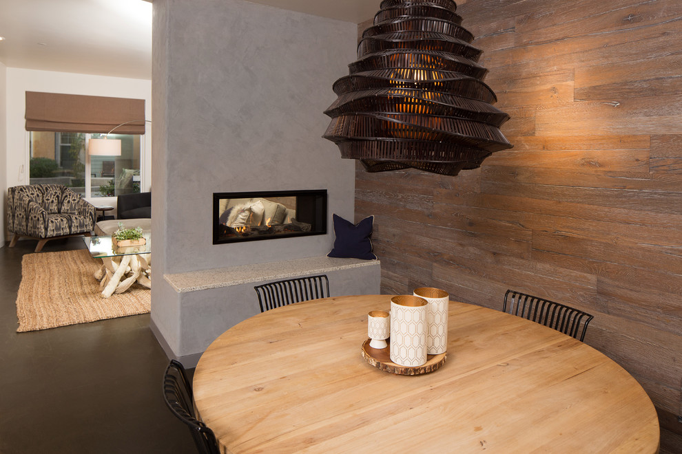 На фото: большая гостиная-столовая в современном стиле с коричневыми стенами, бетонным полом, двусторонним камином, фасадом камина из бетона и серым полом с