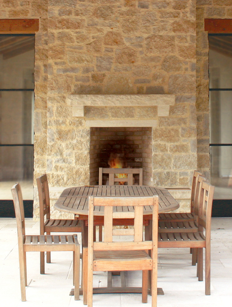 Foto di una sala da pranzo aperta verso la cucina country di medie dimensioni con camino classico e cornice del camino in pietra
